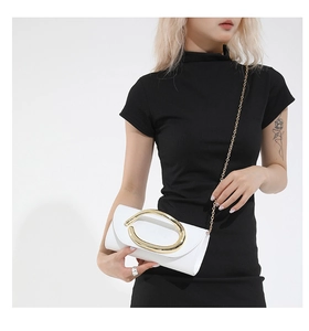 Detail of white leather shoulder bag featuring a large gold oval ring and elegant chain strap