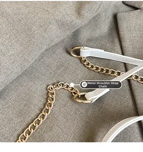 Detail of the high-quality gold metal chain and white leather strap on a small square bag