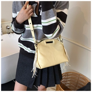 Détail d'un sac bandoulière jaune clair avec franges porté par un mannequin