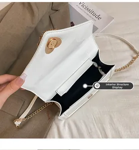 Detail view of the white patent leather bag interior with gold heart lock and chain