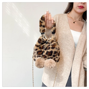 Close-up of leopard print plush bucket bag with drawstring and fluffy pompom details