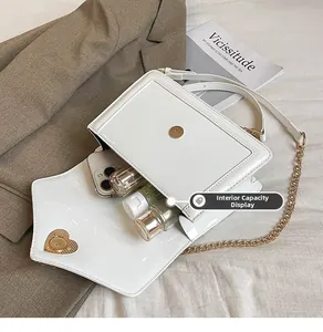 White patent leather bag interior capacity showing smartphone and lipstick with gold heart lock