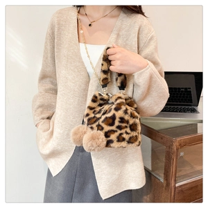 Detail of leopard print plush bucket bag featuring soft pom-poms and gold chain strap