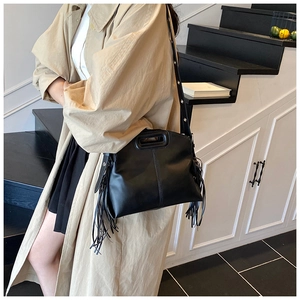 Détail du sac bandoulière noir avec de longues franges et une poignée évidée