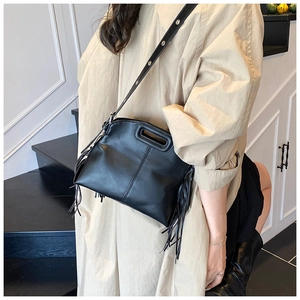 Détail du sac bandoulière noir avec glands latéraux et poignée découpée au design unique