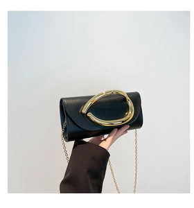 Close-up of black leather clutch with oversized gold metal ring handle and chain strap