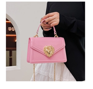 Detail of pink patent leather bag with a gold hollow heart and pearl embellishments