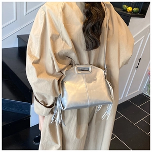 Sac bandoulière argenté à franges avec finition métallique porté sur un trench beige