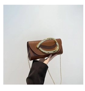 Detail of a brown leather clutch with a large gold metal ring handle and chain strap