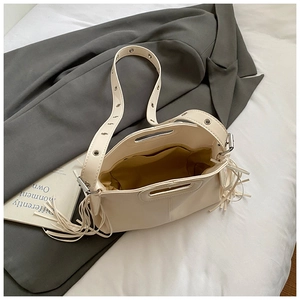 Détail du sac à main crème avec glands, bandoulière à œillets et doublure jaune