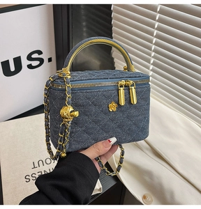 Macro detail of blue denim quilted mini bag with gold curved handle and floral charm