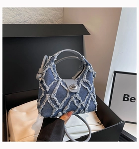 Dettaglio della borsa in denim trapuntata con bordi sfrangiati in una confezione regalo