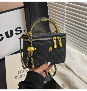 Detail of black quilted mini chain bag with gold metal handle and floral embellishments