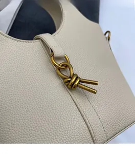 Gros plan d'un sac seau en cuir beige grainé avec boucle en métal doré vieilli