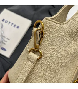 Détail du cuir crème grainé litchi et des finitions métalliques dorées vintage du sac
