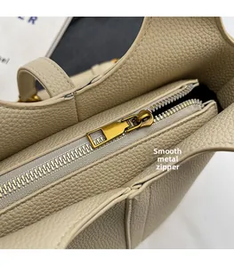 Gros plan sur la fermeture éclair en métal doré et le cuir grainé du sac beige