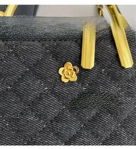 Detailed macro view of black quilted fabric with gold camellia metal hardware and zipper