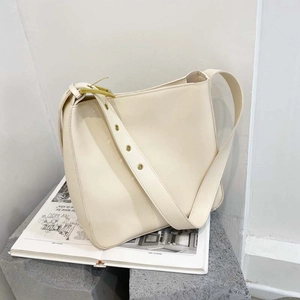 Minimalist cream leather bucket bag with wide adjustable shoulder strap and gold hardware