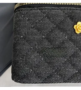 Detail of black quilted denim bag with gold zipper and 3D metal camellia flower charm