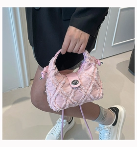 Dettaglio della borsa in denim rosa con bordi sfrangiati e chiusura a girello in metallo argento