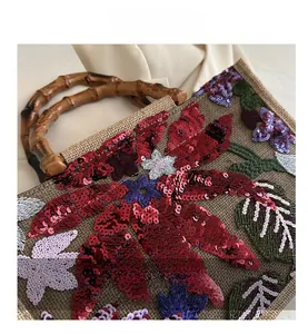 Detail of embroidered floral sequins on brown linen handbag with bamboo handle