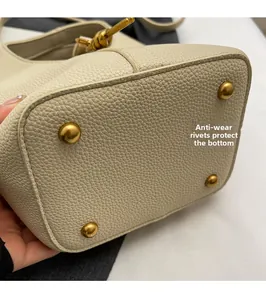 Détail des rivets de protection en métal doré sur le fond du sac seau blanc cassé