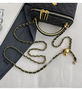 Detail of black quilted chain bag featuring gold flower logo and adjustable strap