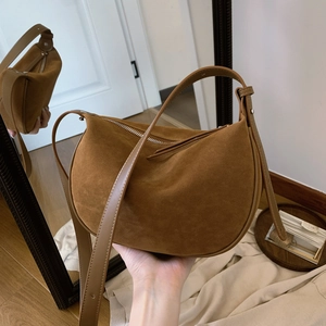 Brown suede crescent shoulder bag with silver zipper and retro minimalist design style