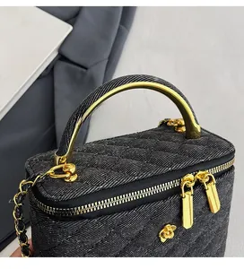 Detailed view of black quilted vanity bag with gold handle and floral hardware