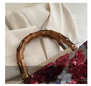 Close-up of retro canvas handbag with bamboo handle, red sequins and floral embroidery
