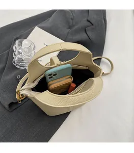 Détail de l'espace intérieur du sac seau en cuir beige avec téléphone et portefeuille
