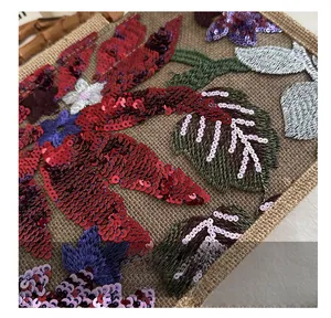 Detailed close-up of intricate floral embroidery and sequins on a woven fabric handbag