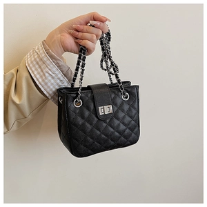 Detail of black quilted leather handbag with silver chain strap and twist lock