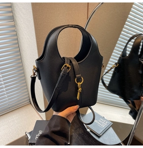 Détail du sac seau noir en cuir grainé avec finitions dorées et poignée creuse