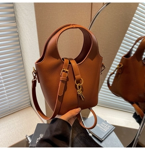 Détail du sac seau en cuir marron grainé avec ferrures dorées et lien décoratif élégant