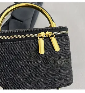 Detail of black quilted chain bag with gold camellia ornament and metal ring handle