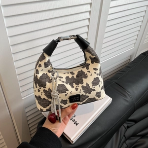 Minimalist cow print crescent hobo bag with red heart tassel charm and black handle
