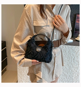Dettaglio borsa in denim nero con cuciture a rombi, frange e chiusura in metallo argentato