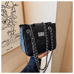 Detail of quilted texture leather and silver metal twist lock on the crossbody bag