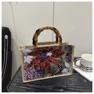 Detail of jute tote bag featuring floral sequin embroidery and a natural bamboo handle