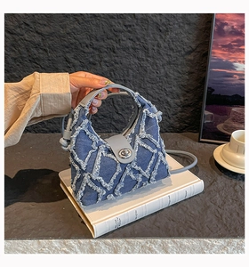 Dettaglio borsa a tracolla in denim blu con cuciture a rombi e chiusura in argento
