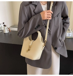 Détail d'un sac seau en cuir grainé blanc crème avec un fermoir rotatif en métal doré