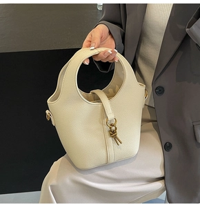 Détail du sac seau en cuir crème avec poignée creuse et boucle nœud dorée élégante