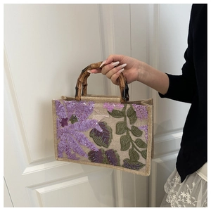 Detail of jute tote bag featuring floral sequin embroidery and natural bamboo handles