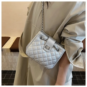 Close-up of silver quilted chain bag with metallic texture and a rotating metal lock