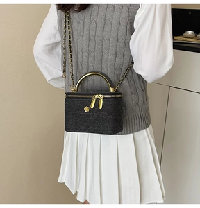 Detail of tweed crossbody bag with gold metal handle and chain strap on model
