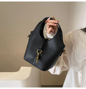 Vue détaillée du sac seau noir en cuir litchi avec boucle dorée et pendentif nœud