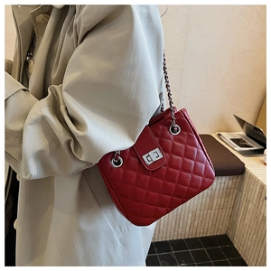Close-up of red quilted chain bag with silver twist lock and polished leather texture