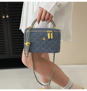 Macro view of blue denim quilted mini bag with gold chain and camellia flower detail