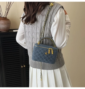 Blue denim quilted box bag with gold floral clasp and chain strap shown on a model